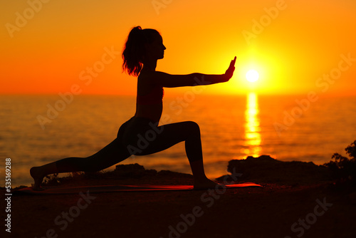 Woman silhouette doing tai chi at sunset photo