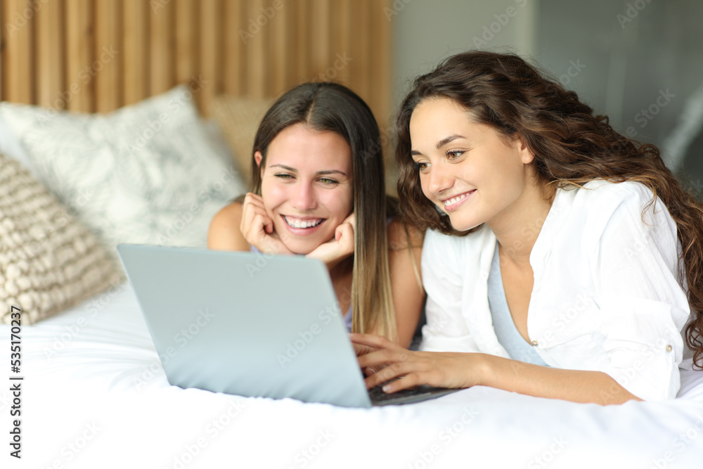 Happy women watching media on laptop on a bed Happy women watching media on laptop on a bed
