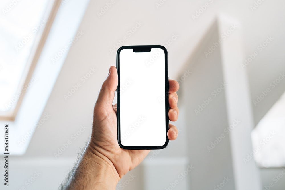 Tourist in hotel room holding smartphone with blank mockup screen for booking and reservation app Tourist in hotel room holding smartphone with blank mockup screen for booking and reservation app