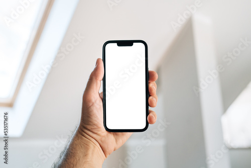 Tourist in hotel room holding smartphone with blank mockup screen for booking and reservation app