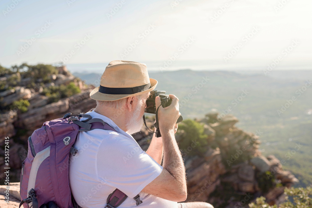 Obraz premium an older hiker sitting on the summit taking a picture