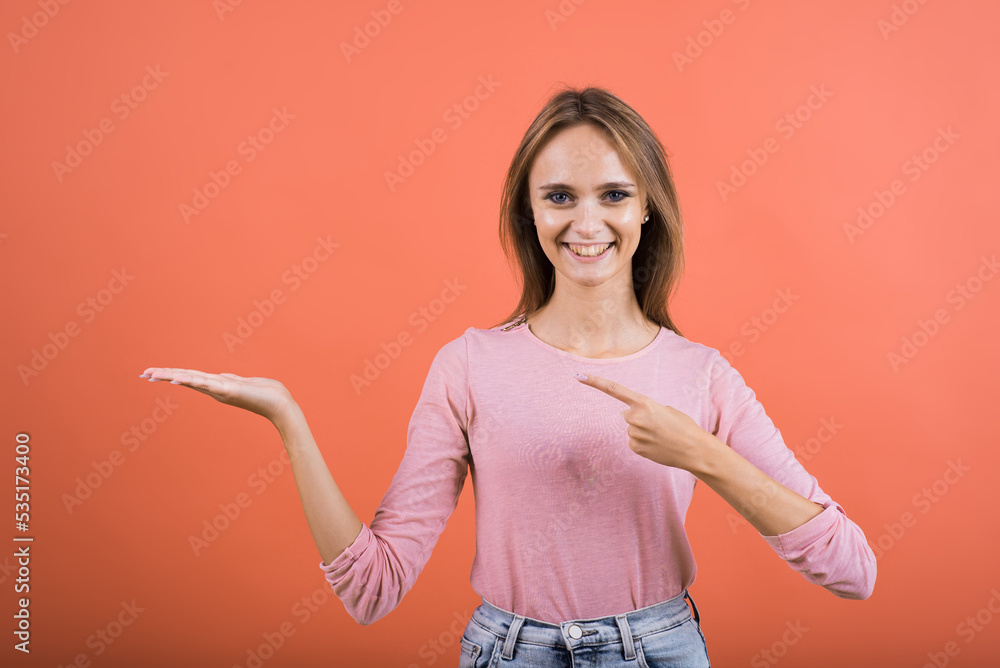 The girl points her finger at the palm with a copy space for advertising on a red background. The girl points her finger at the palm with a copy space for advertising on a red background.