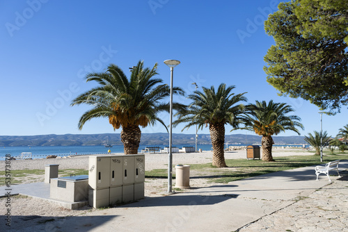 Palms trees on the beach of Omis, Dalmatia, Croatia, with the Adriatic sea in the back and a view on Brac island.