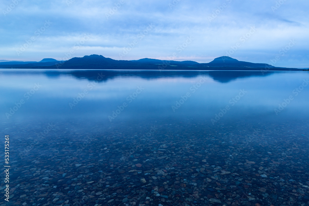 曇り空の下の夜明けの湖。北海道の屈斜路湖。