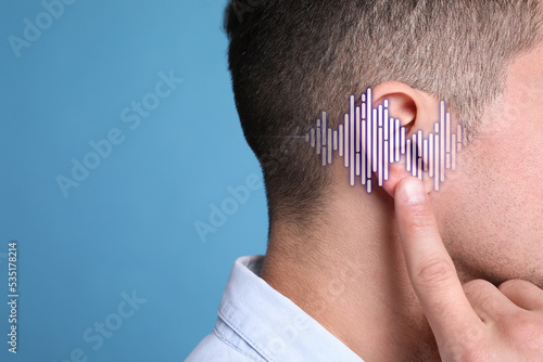 Hearing loss concept. Man and sound waves illustration on light blue background, closeup with space for text photo