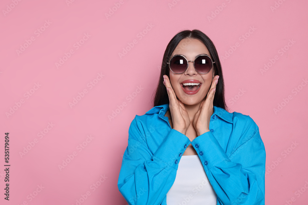 Attractive happy woman in fashionable sunglasses against pink background. Space for text Attractive happy woman in fashionable sunglasses against pink background. Space for text