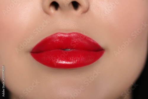 Young woman wearing beautiful red lipstick on dark background  closeup
