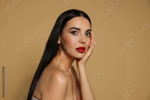 Portrait of young woman wearing beautiful red lipstick on beige background. Space for text