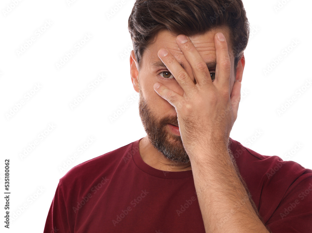 Embarrassed man covering face with hand on white background Embarrassed man covering face with hand on white background