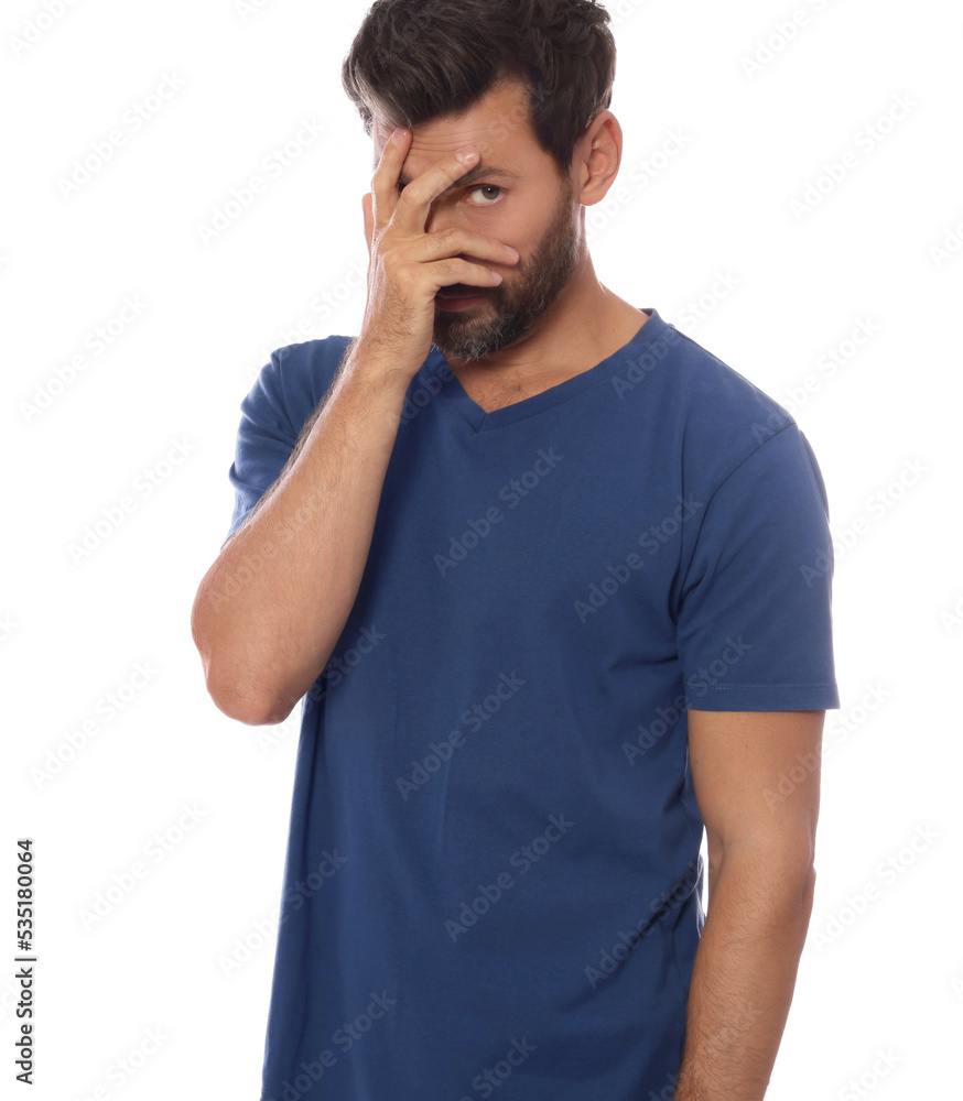 Embarrassed man covering face with hand on white background Embarrassed man covering face with hand on white background