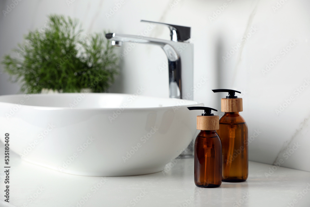Bottles with dispenser caps on white table in bathroom Bottles with dispenser caps on white table in bathroom