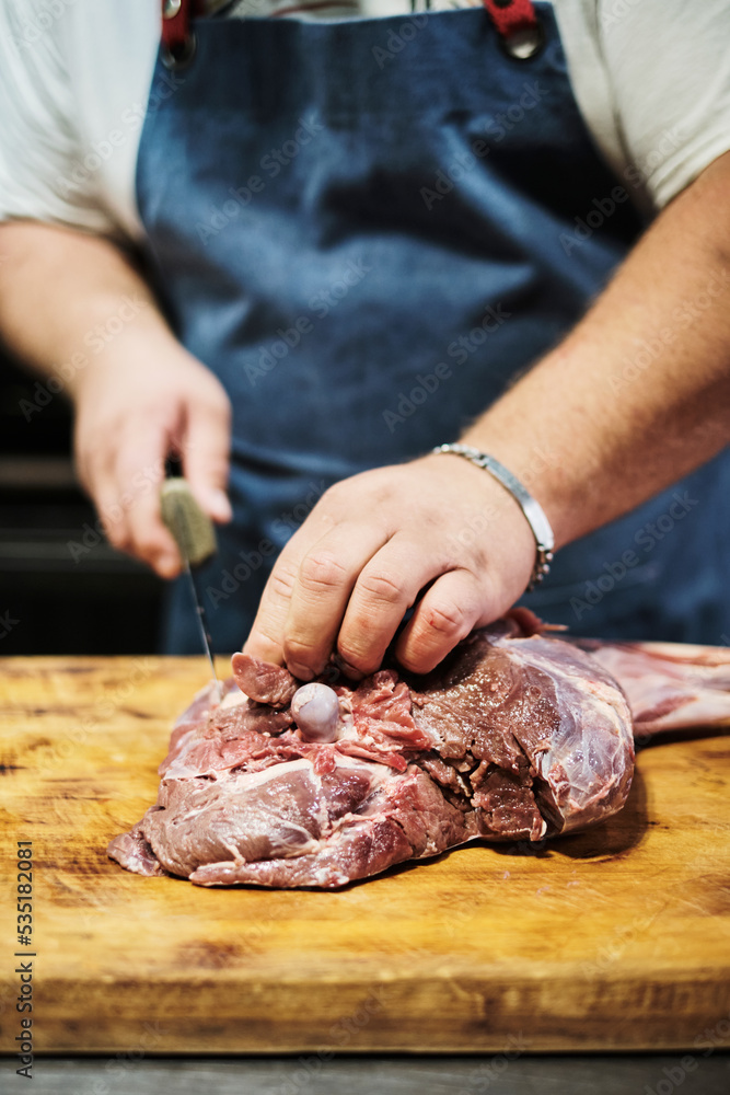 A butcher butchers a leg of lamb for grilling. Pitmaster prepares meat for smoking