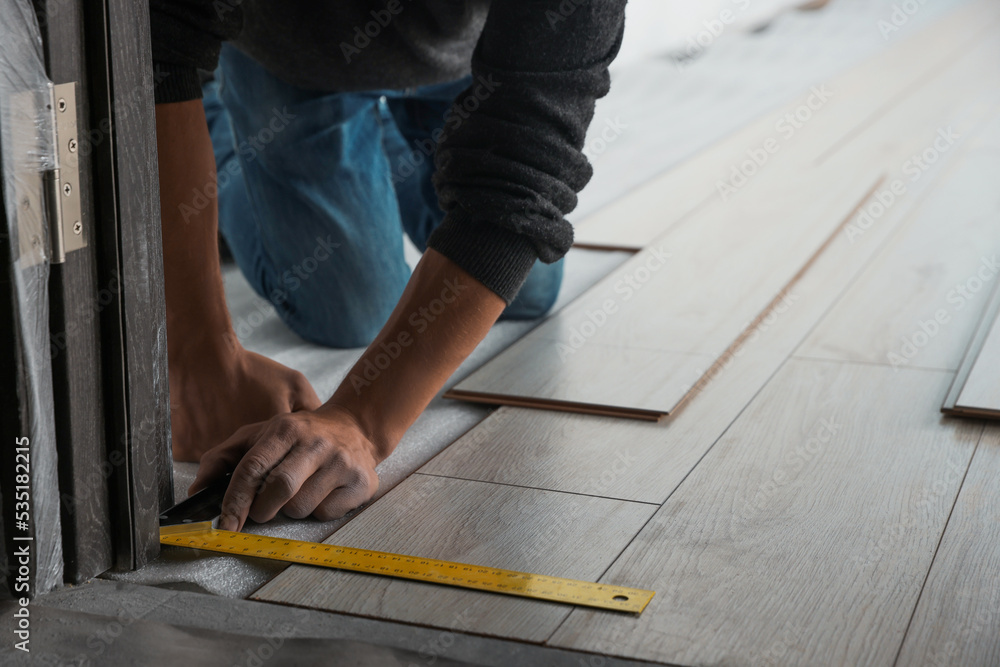 Worker installing new laminate flooring in room, closeup Worker installing new laminate flooring in room, closeup