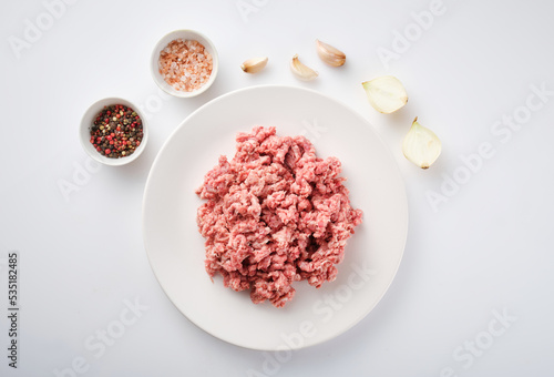 Raw minced meat on the white plate. Fresh pork minced meat on white background. Raw minced pork