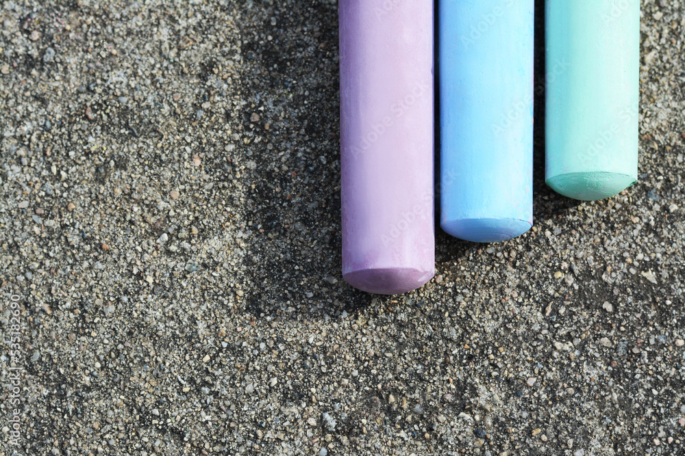 Colorful chalk sticks on asphalt, flat lay. Space for text Colorful chalk sticks on asphalt, flat lay. Space for text