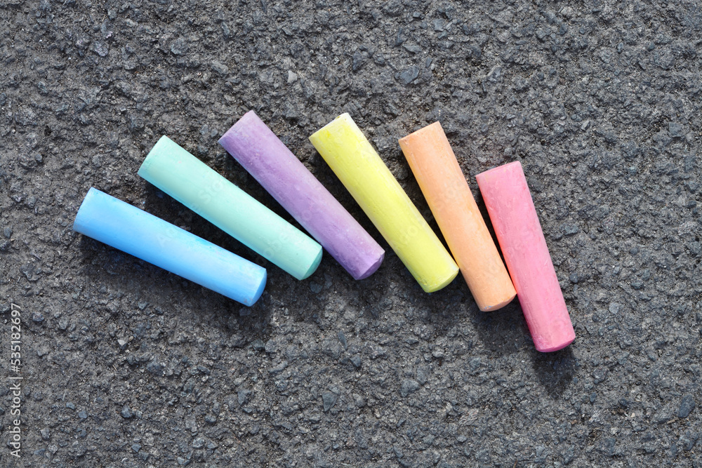 Colorful chalk sticks on asphalt, flat lay Colorful chalk sticks on asphalt, flat lay