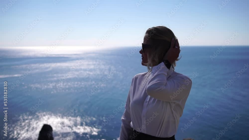 Business woman talking by phone on the sea. Digital nomad, Pretty lady typing on computer by the sea at sunset, makes a business transaction online from a distance. Freelance, remote work on vacation Business woman talking by phone on the sea. Digital nomad, Pretty lady typing on computer by the sea at sunset, makes a business transaction online from a distance. Freelance, remote work on vacation