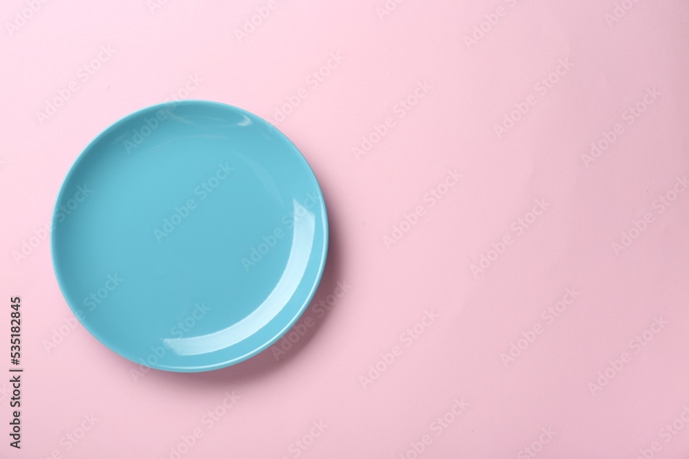 Obraz premium Clean light blue plate on pink background, top view. Space for text