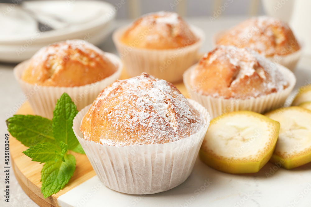 Tasty muffins served with mint and banana on board, closeup Tasty muffins served with mint and banana on board, closeup