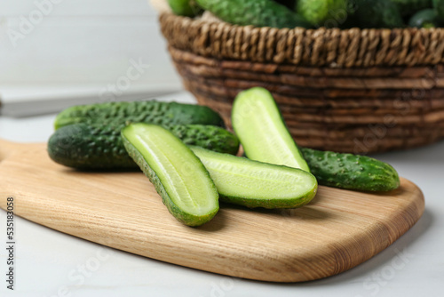 Whole and cut fresh ripe cucumbers on white table