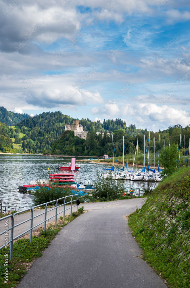 Bicycle route by the lake with a view of the marina and the castle, surrounded by beautiful rocky mountains