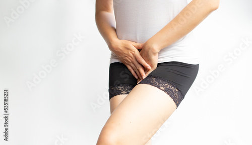 Young woman hand holding pressing her above crotchon withe isolate background. Period Pain or vaginal or urinary infection woman health Problem. Health Issues Concept.