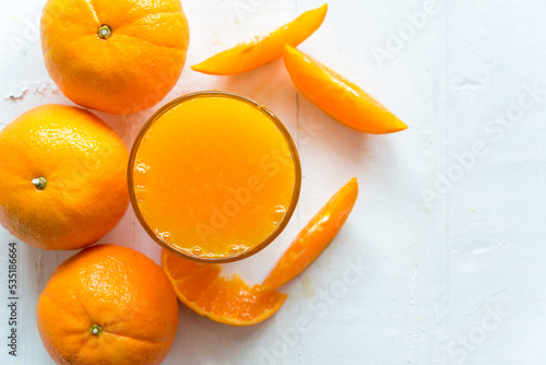 Fresh orange juice in the glass with orange fruit on wood background from top view © samurai