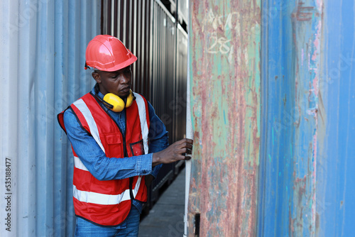 Foreman opens container door to view goods inside and control loading containers box. Engineer or worker with helmet work at container cargo site and checking industrial container cargo freight ship.