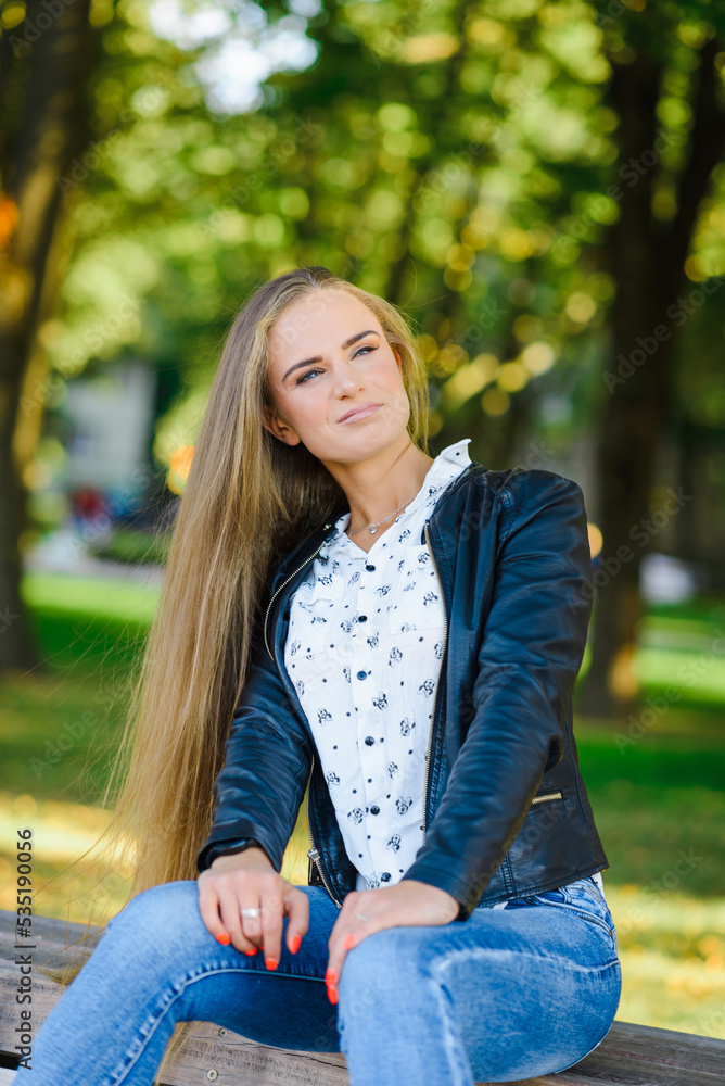 A beautiful fashion young city woman sitting on a bench.Summer,autumn day.Klaipeda,Lithuania.09-02-2022. A beautiful fashion young city woman sitting on a bench.Summer,autumn day.Klaipeda,Lithuania.09-02-2022.