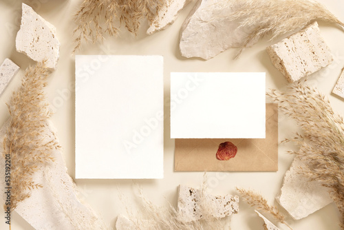 Blank cards near beige travertine stones and dried pampas grass top view, greeting mockup © katrinshine