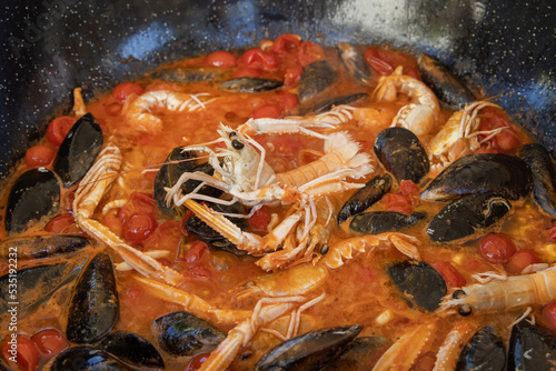 Cooking Italian stew with seafood and tomatoes in a big frying pan,  close up