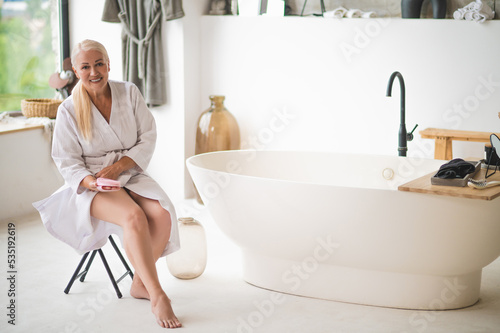 Barefoot woman in the bathrobe preparing for lymphatic drainage self-massage