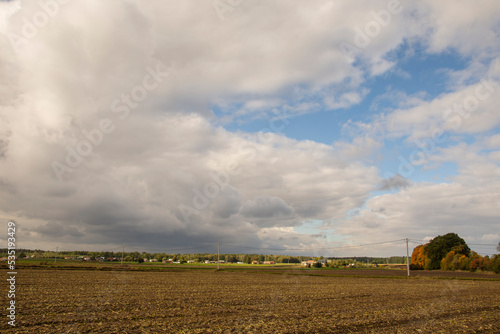 Dark clouds over the plowed field and the village in the background. Autumn.