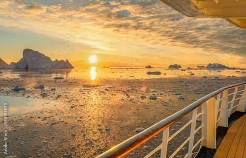 Kreuzfahrtschiff fährt bei einen dramatischer Sonneuntergang / Abendstimmung durch die winterliche Cierva Cove - ein tiefer Meeresarm an der Westseite der Antarktischen Halbinsel, umringt von der Cier