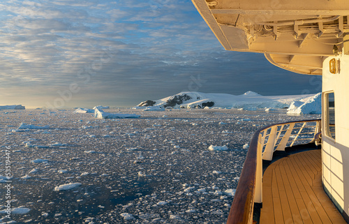 Kreuzfahrtschiff fährt bei einen dramatischer Sonneuntergang / Abendstimmung durch die winterliche Cierva Cove - ein tiefer Meeresarm an der Westseite der Antarktischen Halbinsel, umringt von der Cier photo