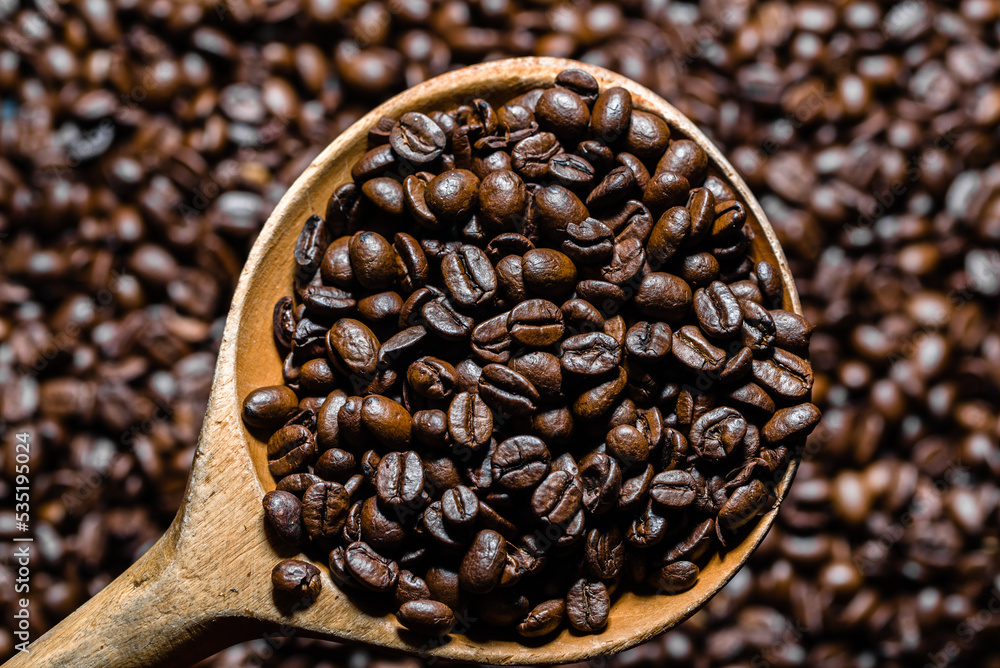 Fototapeta premium Freshly roasted coffee beans in wooden scoop. Black coffee background.