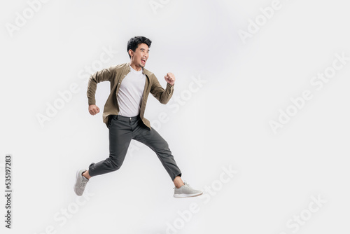 Full length Asian man running jumping in air gesture with happy smile on isolated white background. Cool man joyful running in copy space. Studio short.
