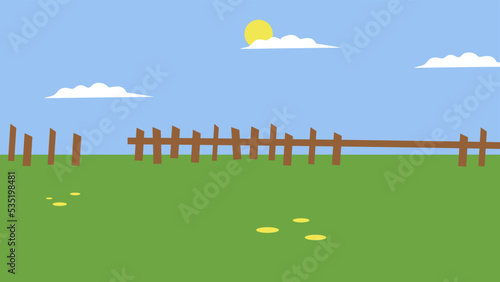 Glade with green grass and a fence on a sunny day