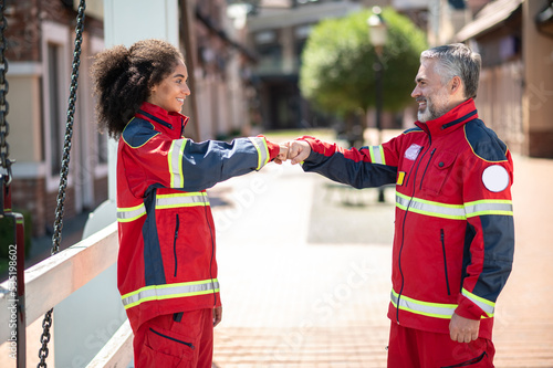 Two joyful paramedics greeting each other outdoors