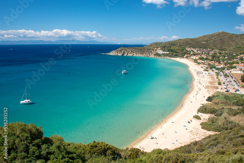 Aerial view on the beach Solanas with white sand, hills with green vegetation, sea with blue transparent water and village in the province Sinnai. Location Sardinia, Italy. 