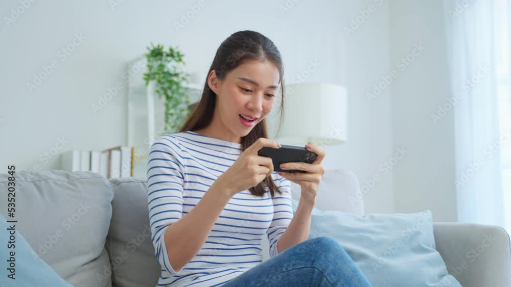 Asian young beautiful woman playing mobile game on smartphone at home. Asian young beautiful woman playing mobile game on smartphone at home.