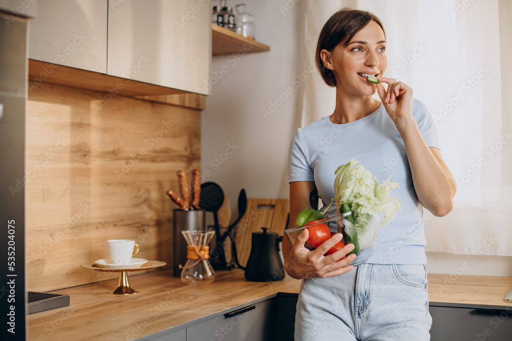 Woman holding bowl full of vegetables at the kitchen