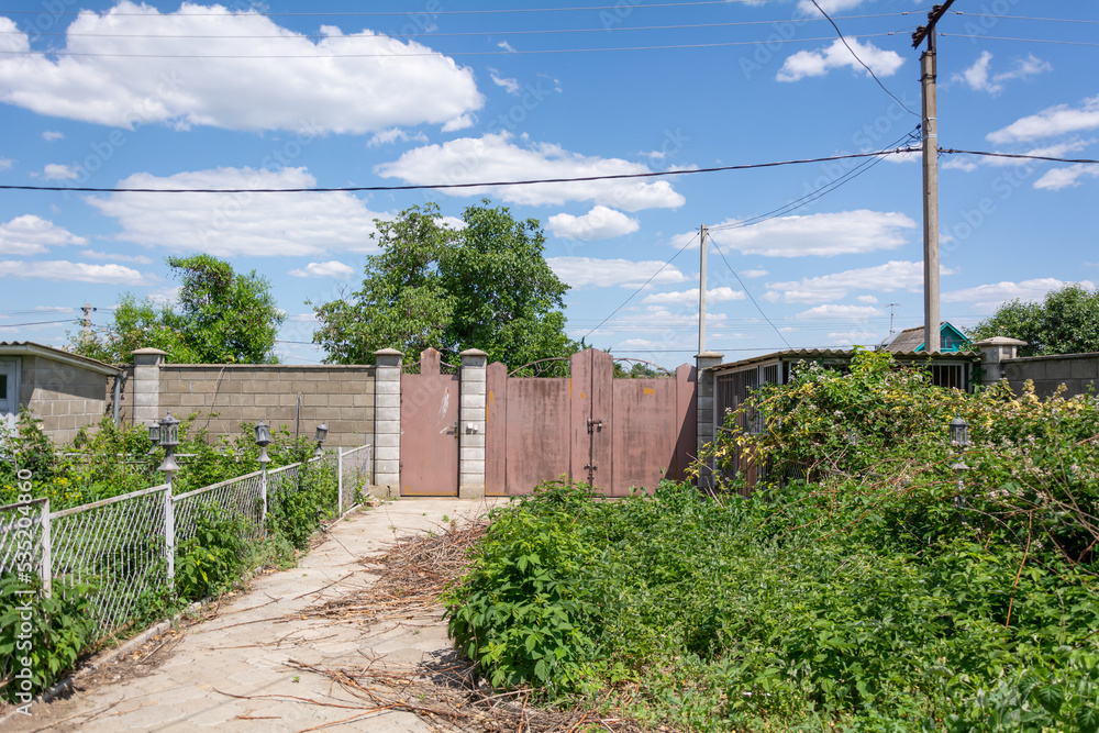 Fence of a private house. View from the yard on fence with patterned iron gates encloses a private house in Transnistrian village