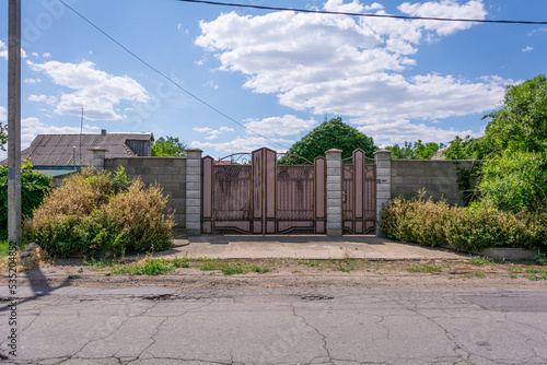 Fence of a private house. View from the street on fence with patterned iron gates encloses a private house in Transnistrian village photo