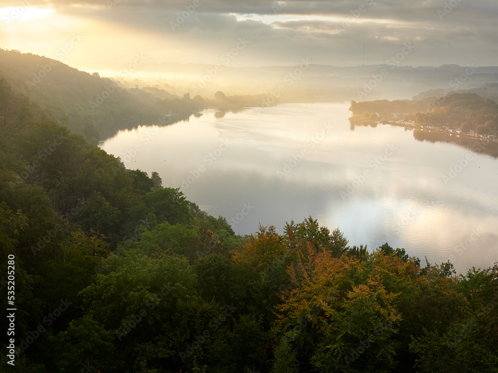 Essen, Germany - View of Lake Baldeneysee and Ruhr river at foggy sunrise. A beautiful autumn landscape. Gold autumn. Essen, Germany - View of Lake Baldeneysee and Ruhr river at foggy sunrise. A beautiful autumn landscape. Gold autumn.