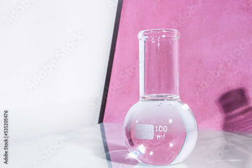 Transparent glass flask on a pink background. science research chemistry banner laboratory background.