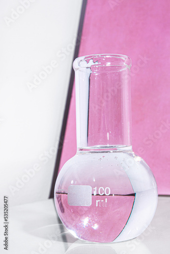 Transparent glass flask on a pink background. science research chemistry banner laboratory background.