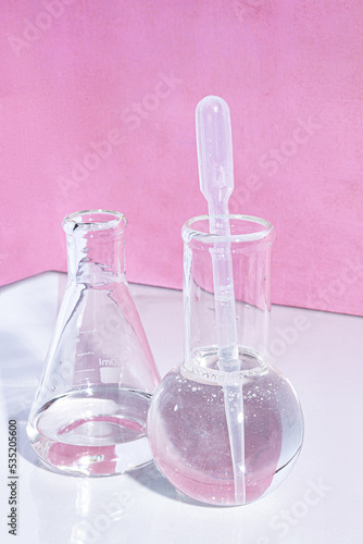 Transparent glass flask on a pink background. science research chemistry banner laboratory background.