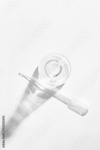 Transparent glass flask on a white background. science research chemistry banner laboratory background. Serum with a pipette in the laboratory. Cosmetic research.