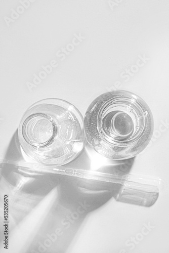 Transparent glass flask on a white background. science research chemistry banner laboratory background. Serum with a pipette in the laboratory. Cosmetic research.